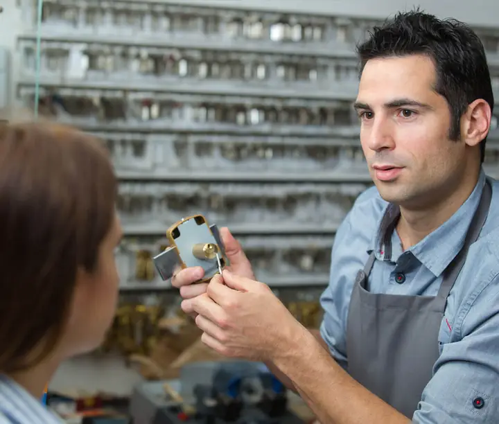 A specialist showing lock hardware to a customer at the counter