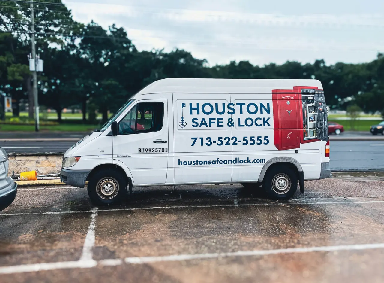 A white Houston Safe & Lock service van with the company name and phone number on its side, parked in a Houston lot