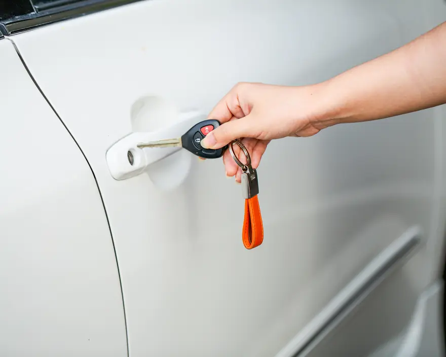 A driver unlocking a car door with a key and remote