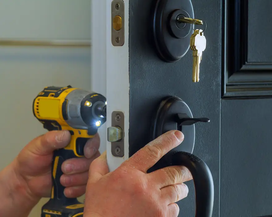 A locksmith installing a new deadbolt with a cordless drill