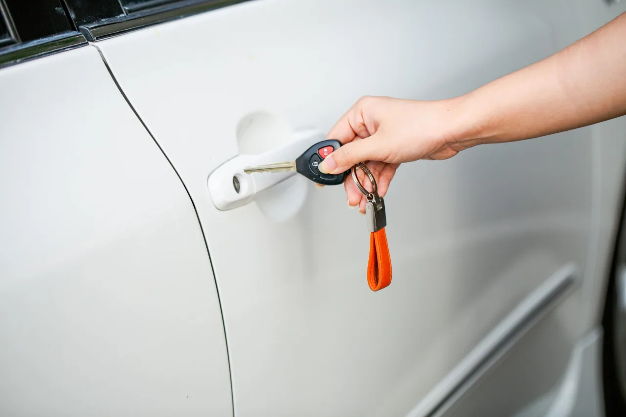 Hand holding a vehicle key beside a car door