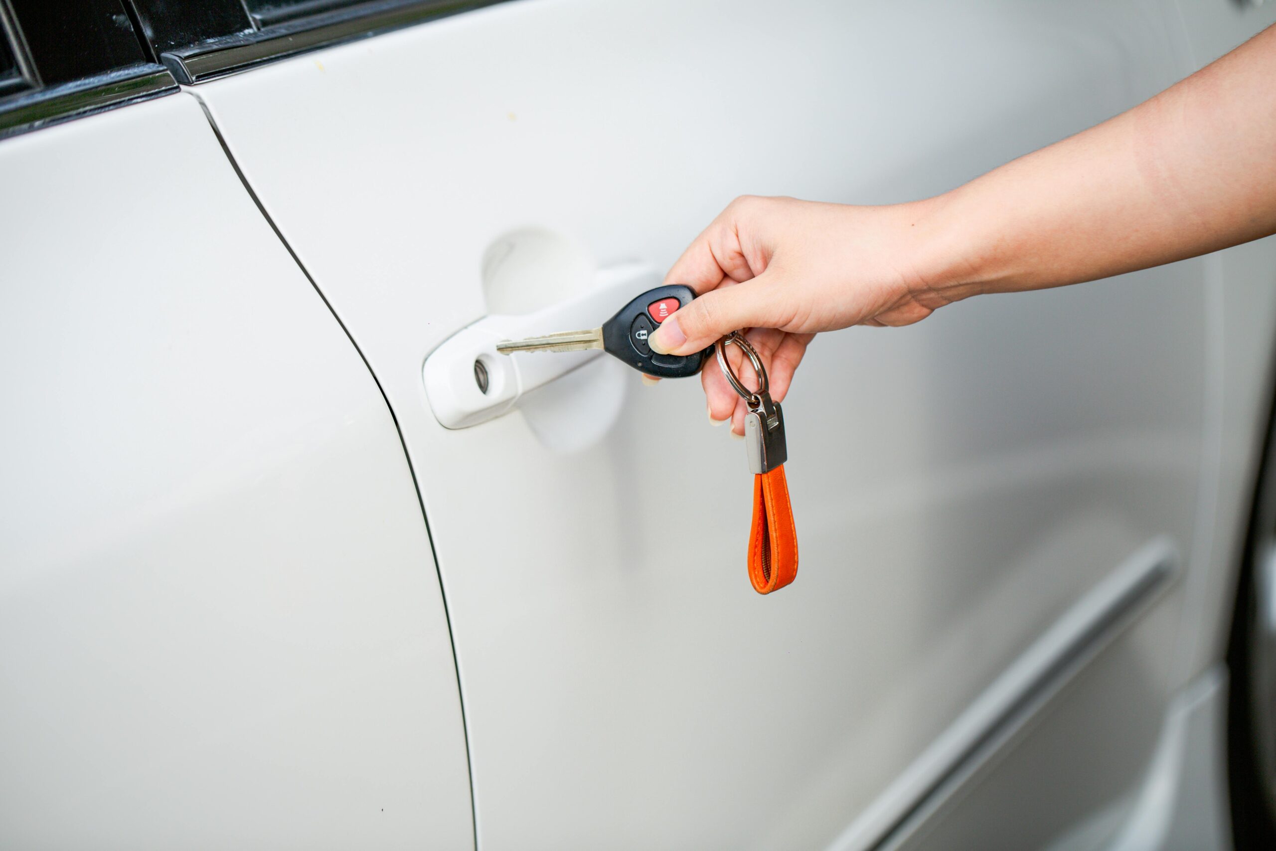 Hand holding a vehicle key beside a car door