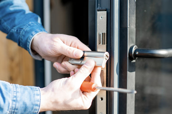 Technician installing a lock cylinder in a commercial door